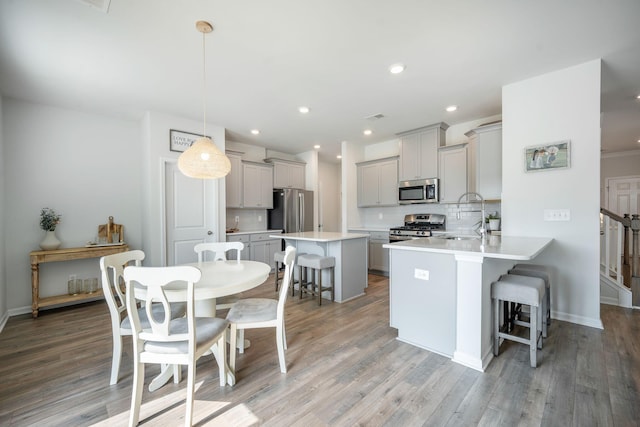 705 Squire Pope Rd, Summerville, SC 29486 - kitchen with stainless steel appliances, a breakfast bar area, a sink, gray cabinets, and decorative backsplash