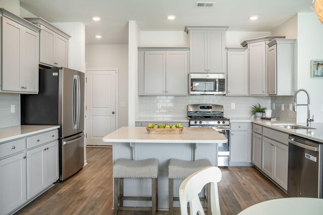 705 Squire Pope Rd, Summerville, SC 29486 - kitchen featuring appliances with stainless steel finishes, a sink, gray cabinetry, decorative backsplash, and a kitchen breakfast bar
