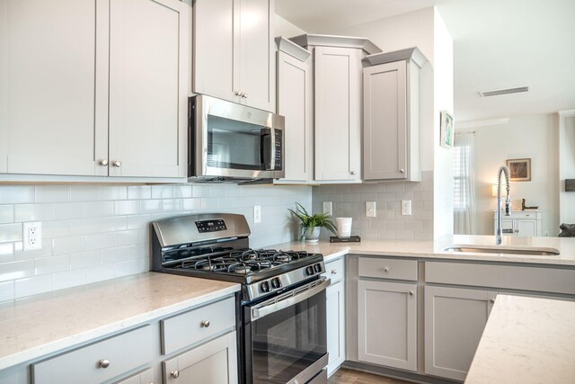 705 Squire Pope Rd, Summerville, SC 29486 - kitchen featuring stainless steel appliances, a sink, gray cabinets, decorative backsplash, and light stone countertops