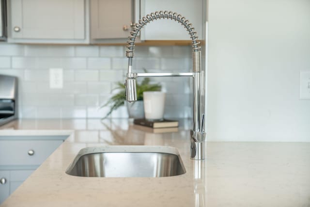 705 Squire Pope Rd, Summerville, SC 29486 - kitchen view of decorative backsplash, a sink, light stone countertops, and gray cabinetry