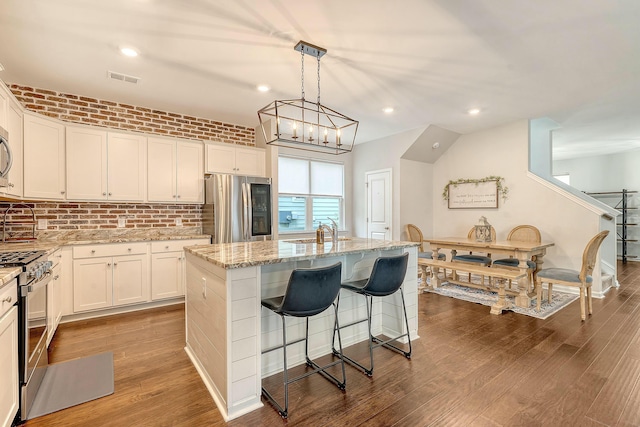 kitchen featuring light stone counters, dark wood-style flooring, visible vents, and stainless steel appliances