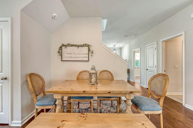 dining area with visible vents, baseboards, vaulted ceiling, and wood finished floors