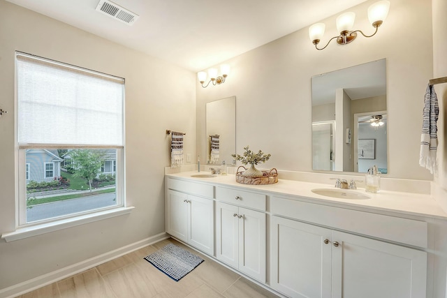bathroom with double vanity, visible vents, baseboards, and a sink