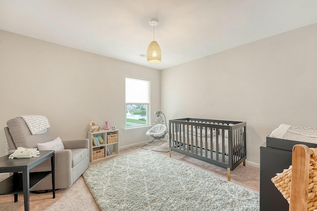 carpeted bedroom with a crib and baseboards
