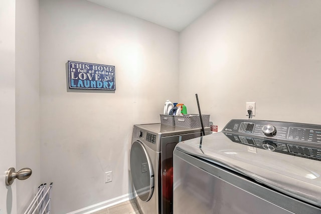 washroom with baseboards, washer and dryer, and laundry area
