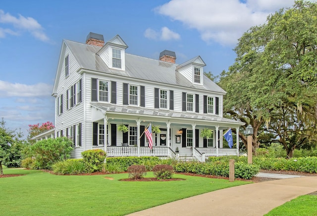 view of front of home featuring a front yard, a porch, and a chimney