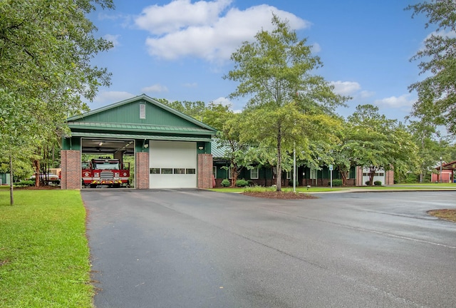 view of front of house with a standing seam roof, metal roof, a front lawn, brick siding, and a garage