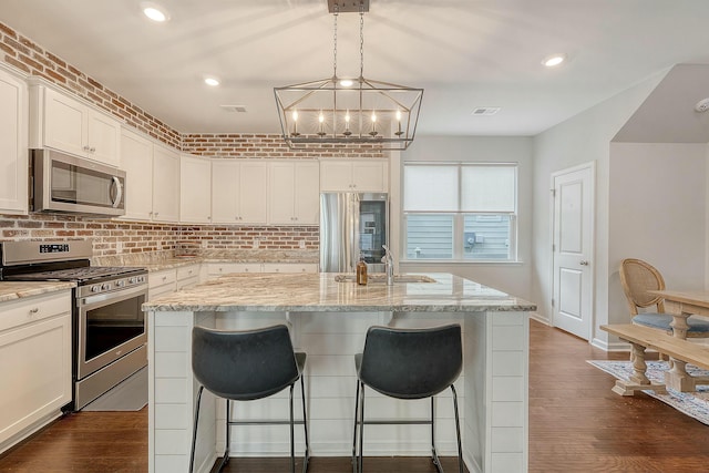 kitchen with a sink, white cabinets, appliances with stainless steel finishes, and dark wood finished floors