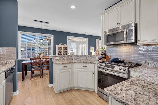 kitchen with white cabinetry, kitchen peninsula, pendant lighting, and stainless steel appliances