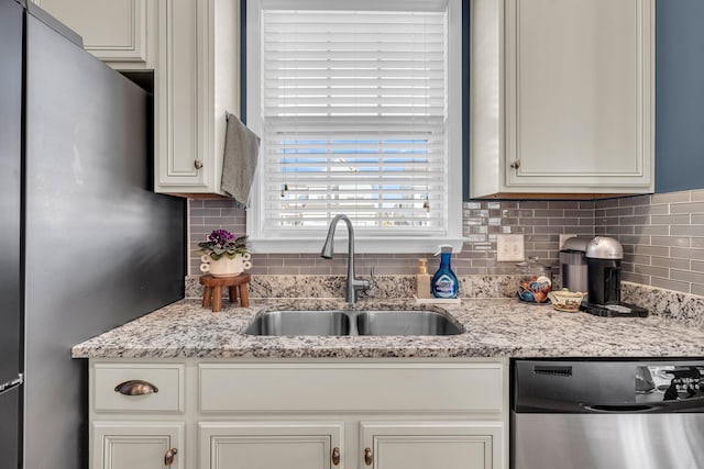 kitchen with white cabinetry, appliances with stainless steel finishes, backsplash, light stone countertops, and sink