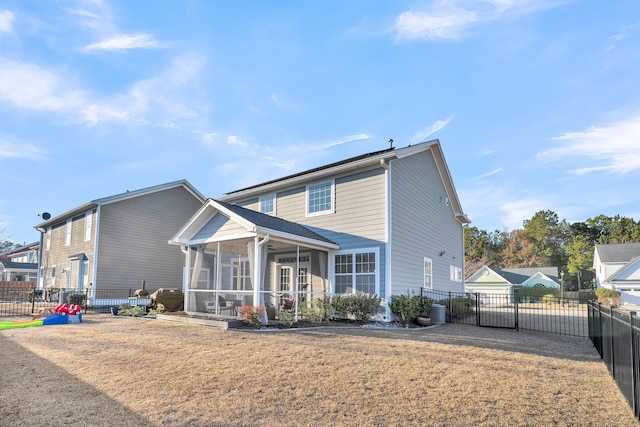 rear view of house with a lawn and a sunroom