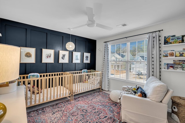 bedroom with ceiling fan and a crib