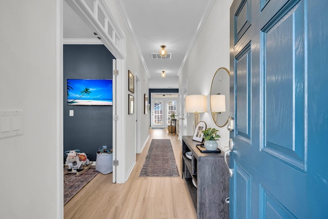 entrance foyer featuring light wood-type flooring, crown molding, and french doors