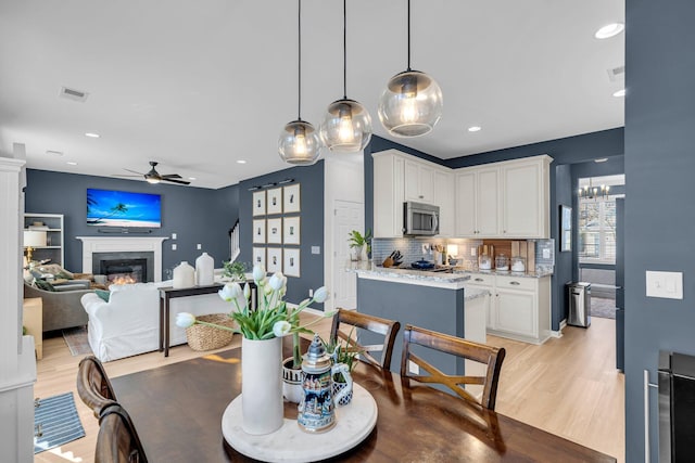 dining space featuring light wood-type flooring, ceiling fan, and beverage cooler