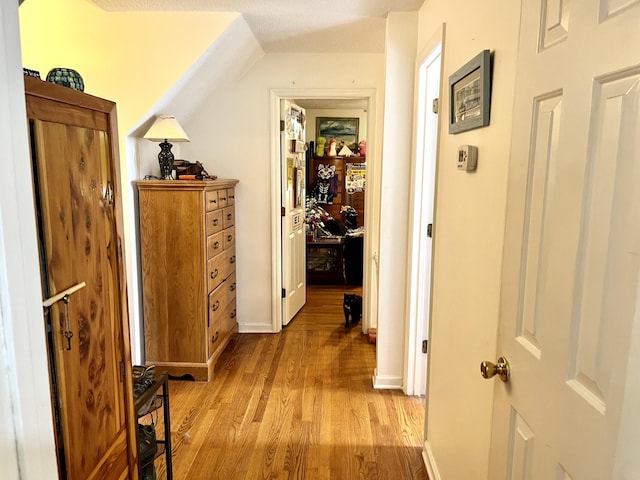 hall featuring vaulted ceiling and light hardwood / wood-style flooring