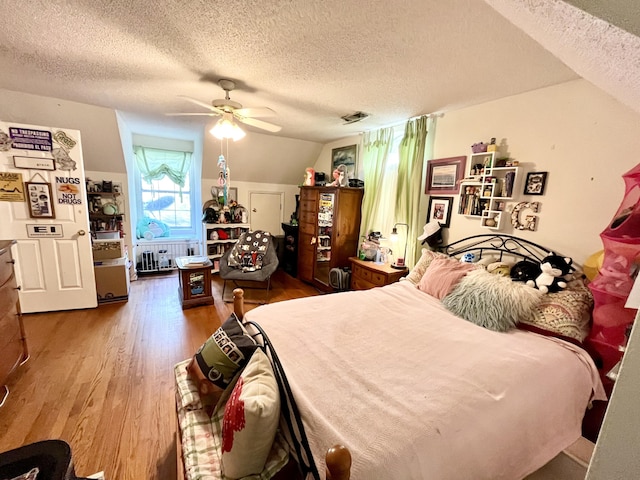 bedroom with hardwood / wood-style floors, ceiling fan, lofted ceiling, and a textured ceiling