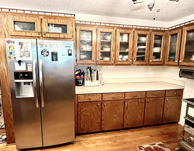 kitchen with a textured ceiling, stainless steel refrigerator with ice dispenser, and light wood-type flooring