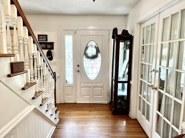 entryway with hardwood / wood-style floors, a textured ceiling, and french doors