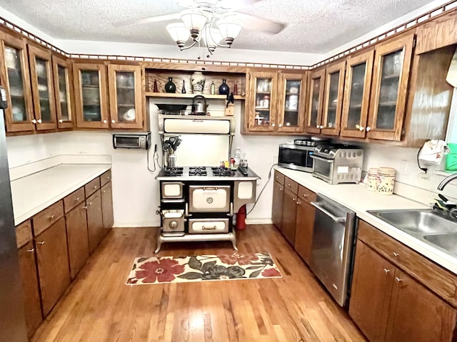 kitchen featuring appliances with stainless steel finishes, light wood-type flooring, a textured ceiling, and sink