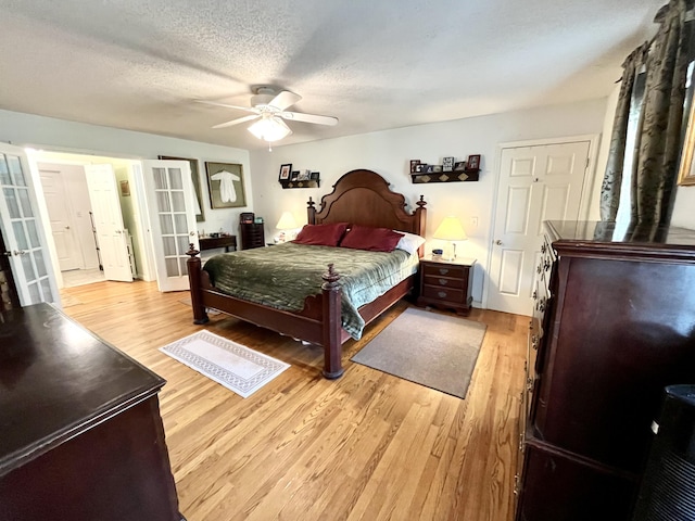 bedroom featuring ceiling fan, light hardwood / wood-style floors, a textured ceiling, and french doors