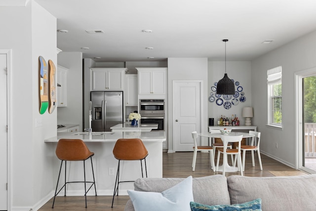 1825 Crossbill Trl, Hanahan, SC 29410 - kitchen with stainless steel appliances, a breakfast bar, a peninsula, light countertops, and white cabinetry