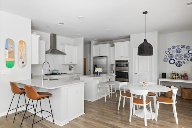 1825 Crossbill Trl, Hanahan, SC 29410 - kitchen with wall chimney exhaust hood, stainless steel appliances, a sink, a breakfast bar, and a peninsula