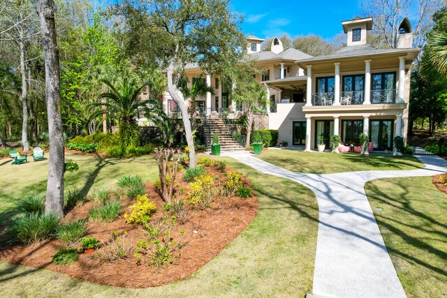 back of house with a lawn and a balcony