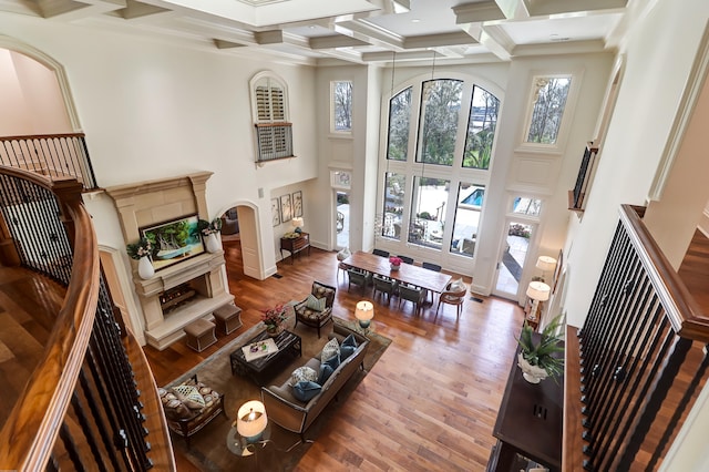 living room with coffered ceiling, dark wood-type flooring, beamed ceiling, a towering ceiling, and crown molding