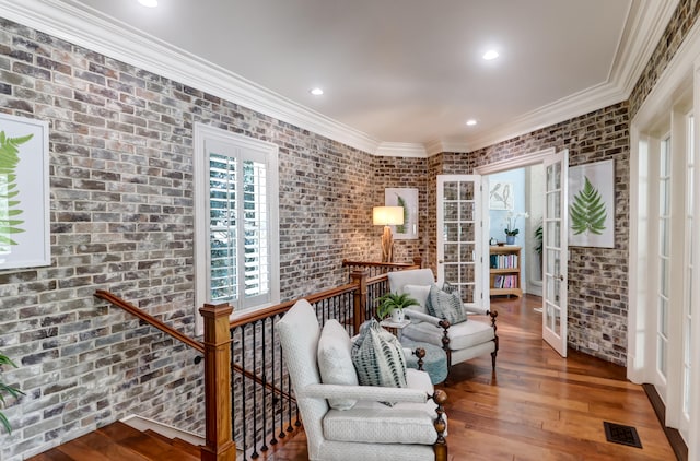 living area with brick wall, french doors, dark hardwood / wood-style flooring, and ornamental molding