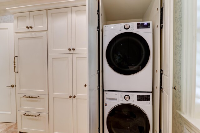 laundry room with stacked washer and dryer and light tile floors