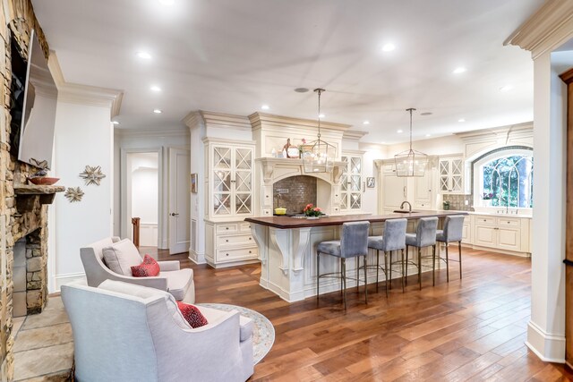 interior space featuring an inviting chandelier, ornamental molding, sink, and light hardwood / wood-style flooring