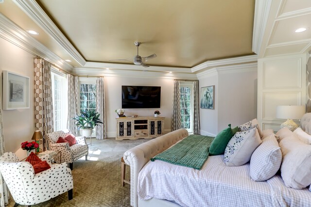 carpeted bedroom featuring a raised ceiling, ceiling fan, ornamental molding, and multiple windows