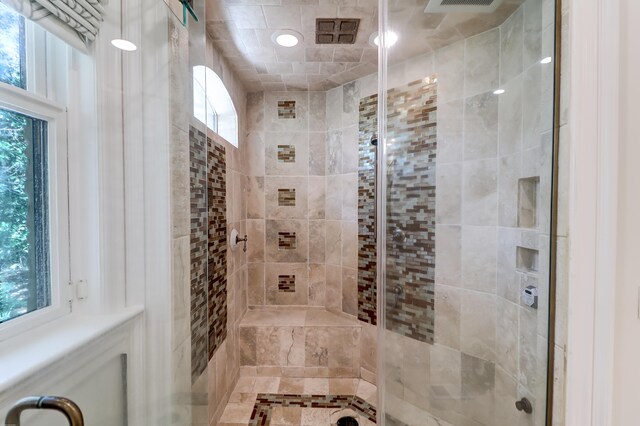 bathroom with a shower with shower door and a healthy amount of sunlight