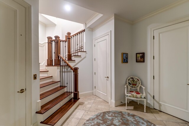 foyer featuring light tile floors and crown molding