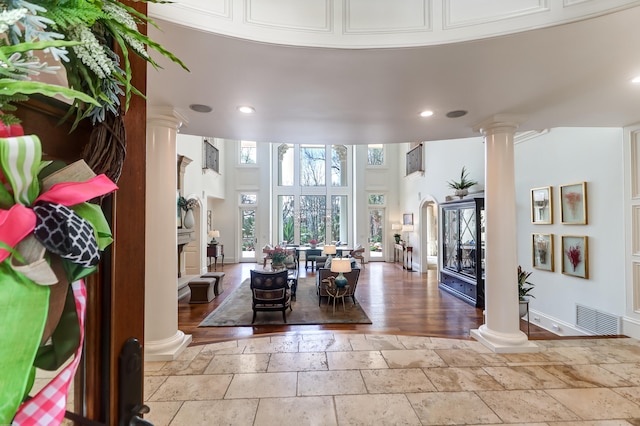 entryway featuring decorative columns, a fireplace, and light tile floors