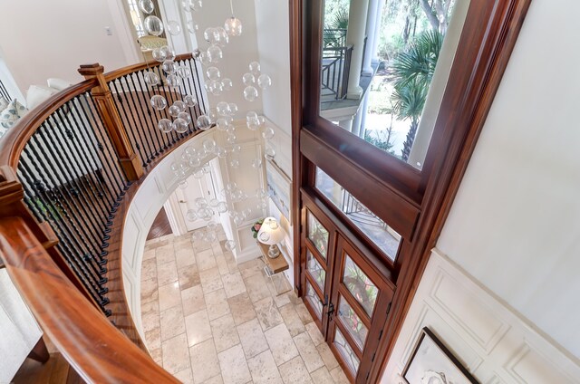 tiled foyer entrance with an inviting chandelier, plenty of natural light, french doors, and a high ceiling