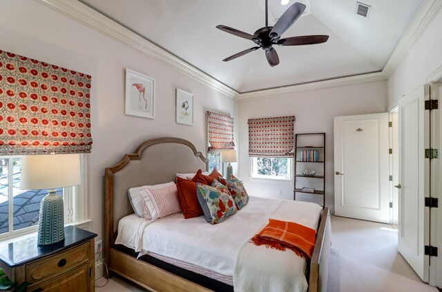 bedroom featuring light carpet, ornamental molding, ceiling fan, and a tray ceiling