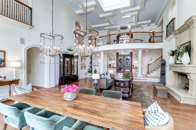 dining space with coffered ceiling, an inviting chandelier, hardwood / wood-style floors, and a towering ceiling