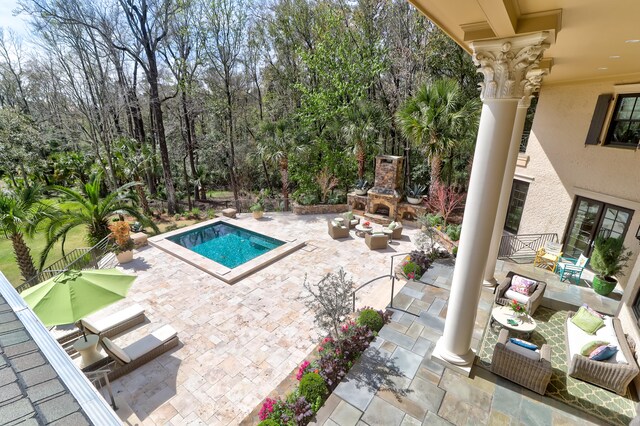 view of pool featuring an outdoor living space with a fireplace and a patio