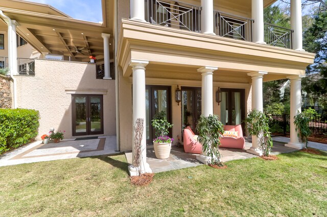 rear view of property with a yard, a balcony, a patio area, and french doors