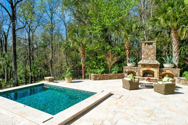 view of pool featuring an outdoor stone fireplace and a patio