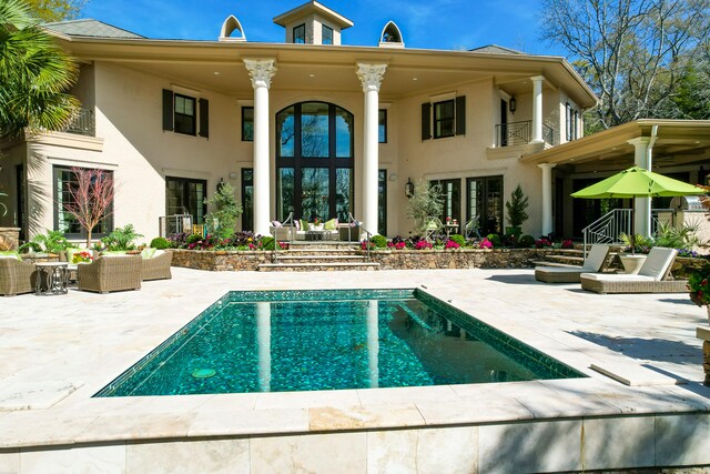 rear view of property featuring a balcony, a patio, and french doors