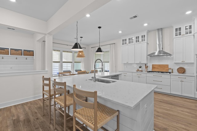 1828 Agate Bay Dr, Mount Pleasant, SC 29466 - kitchen featuring a sink, wall chimney range hood, light wood-style flooring, a center island with sink, and gas cooktop