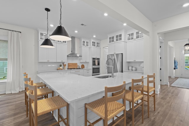 1828 Agate Bay Dr, Mount Pleasant, SC 29466 - kitchen with wall chimney range hood, appliances with stainless steel finishes, a sink, light wood finished floors, and decorative backsplash