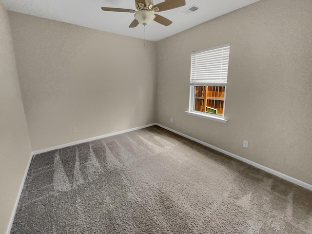 carpeted empty room with visible vents, a ceiling fan, and baseboards