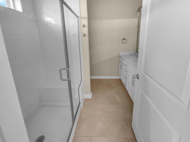 bathroom featuring tile patterned flooring, a stall shower, vanity, and baseboards