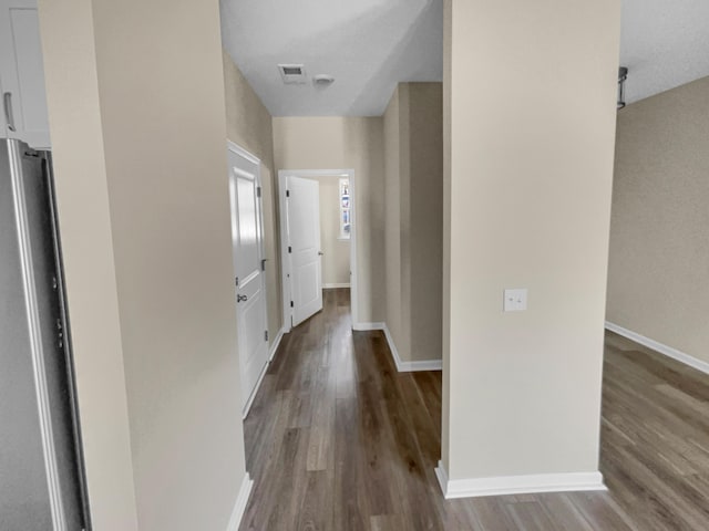 corridor featuring visible vents, baseboards, and wood finished floors