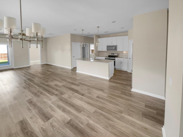 kitchen with light wood-style flooring, open floor plan, white cabinetry, stainless steel appliances, and an inviting chandelier