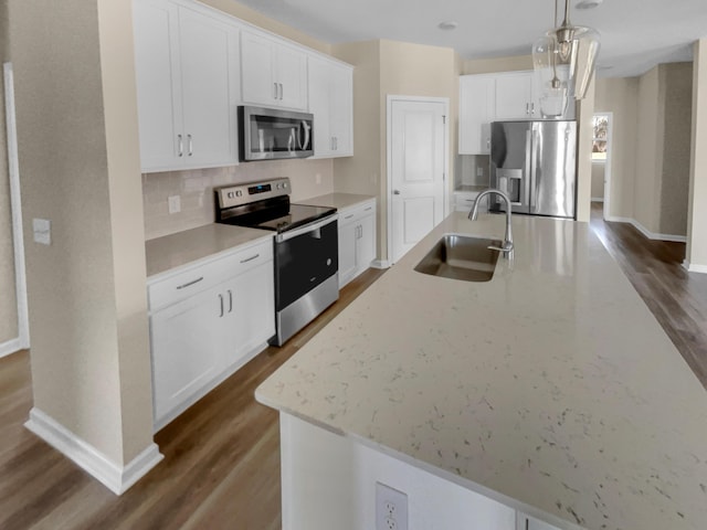 kitchen with a kitchen island with sink, a sink, dark wood-type flooring, appliances with stainless steel finishes, and white cabinetry