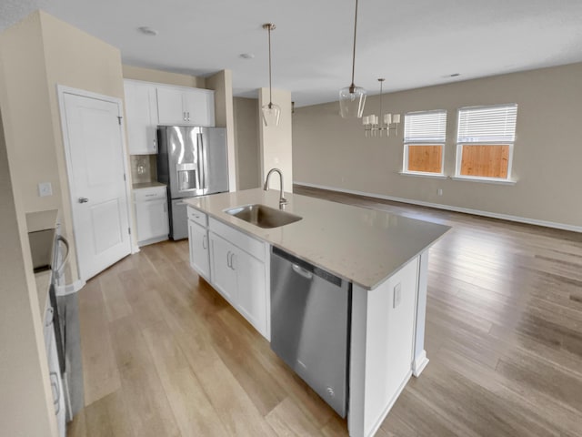 kitchen featuring white cabinets, stainless steel appliances, light wood-style floors, and a sink